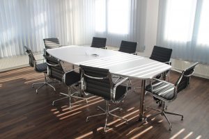 An empty meeting room with a white table and black and chrome chairs around it